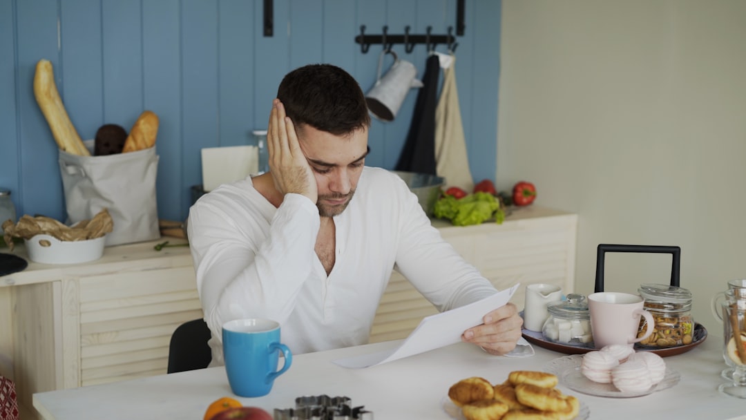 Worried person reviewing overdue debt notices at a kitchen table